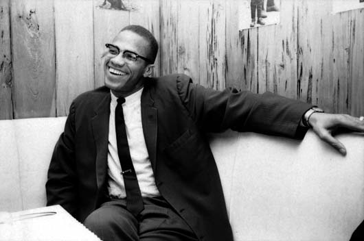 American civil rights leader Malcolm X (1925 - 1965) laughs as he relaxes on a couch in a wood-panelled room, March 1964. (Photo by Truman Moore/Time & Life Pictures/Getty Images)