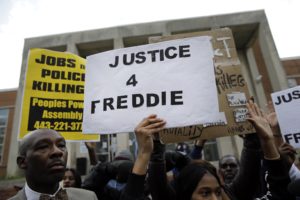 Protestors stand outside of the Baltimore Police Department's Western District police station during a march and vigil for Freddie Gray, Tuesday, April 21, 2015, in Baltimore. Gray died from spinal injuries a week after he was arrested and transported in a police van. (AP Photo/Patrick Semansky)